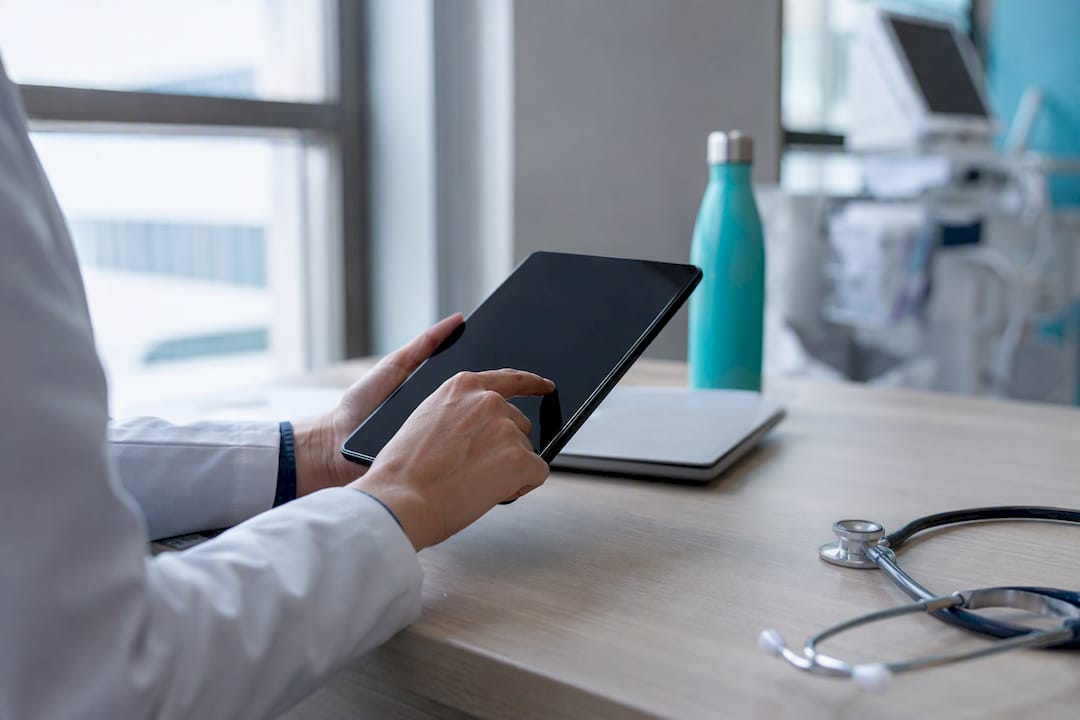 Hands holding tablet in healthcare compliance setting