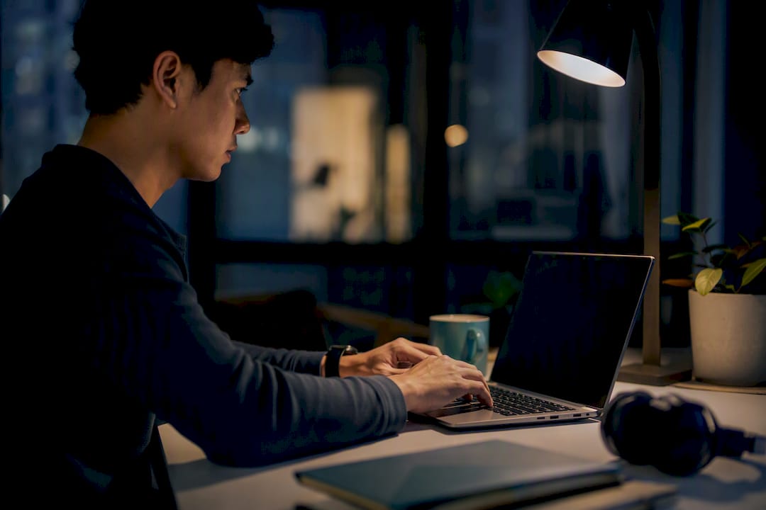 Hands typing on keyboard in dimly lit room